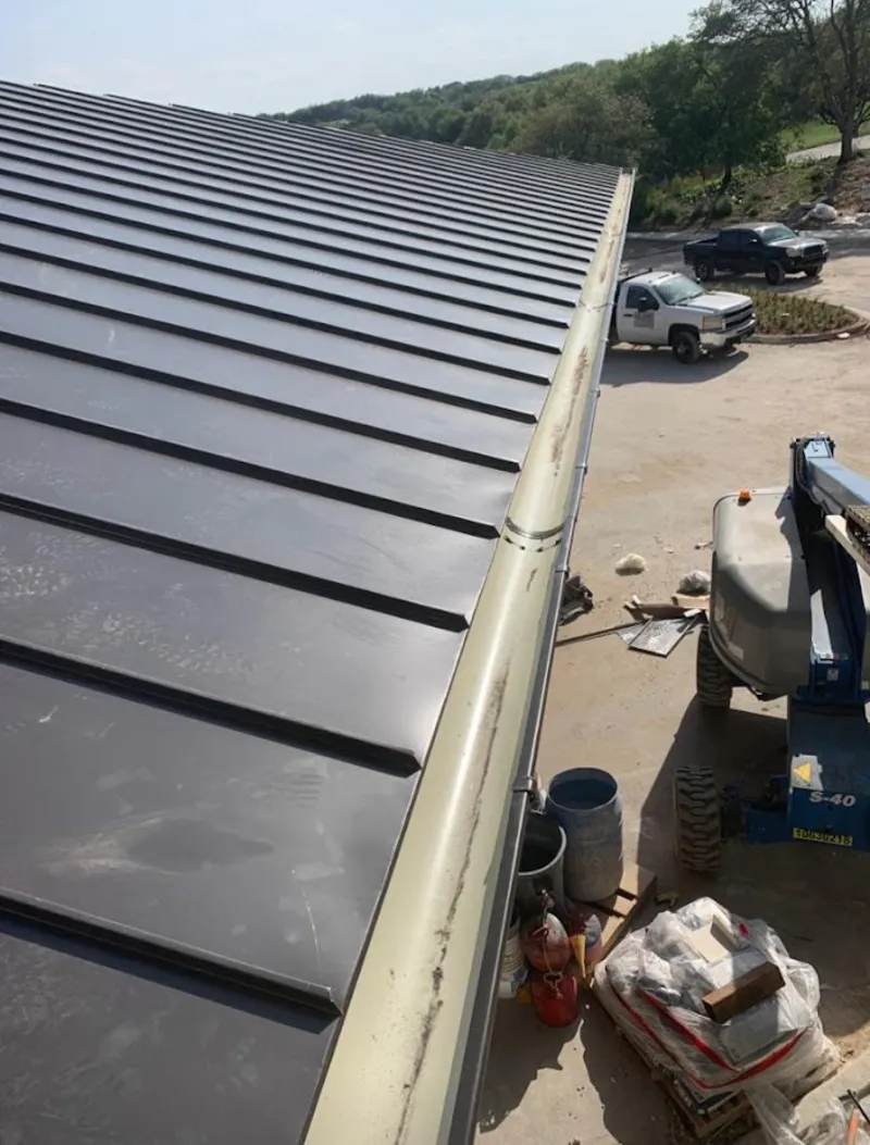 Standing seam panel and gutter detail on a metal roofing jobsite in Bellair-Meadowbrook Terrace